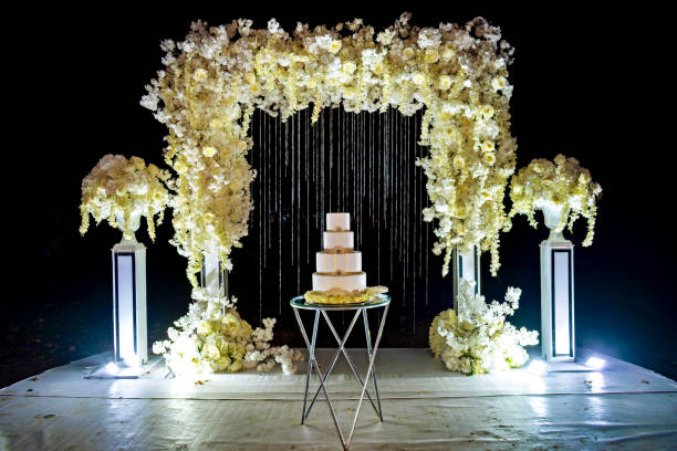 Wedding cake sitting on top of table under flower covered arch